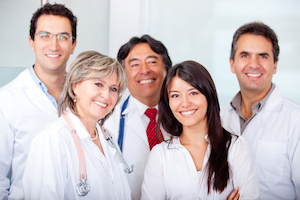 Four Medical Professionals smiling. There is two females and three males
